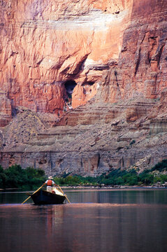 A river guide rowing a wooden dory downstream, Grand Canyon National Park, Arizona.