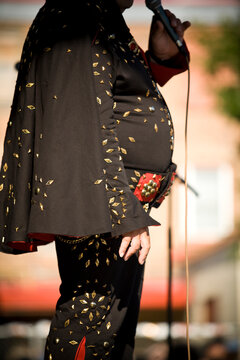 Elvis impersonator in a black costume sings for the crowd.