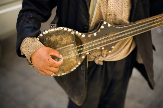 A man plays a traditional string instrument on a street in Lhasa, Tibet.