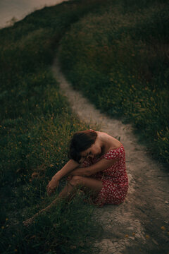 woman put her head on her knees in the summer on the path