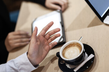Colleagues having a business meeting at a cafe. Drinking coffee and working on laptop and tablet.