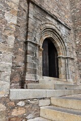 Super rustic heavily patinated stone portal in grey, yellow and white tones with some bricks mixed in at Iglesia Prior de Nuestra Señora del Mayor Dolor church, Aracena, Spain