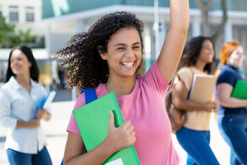 Cheering hispanic female student with group of young adults