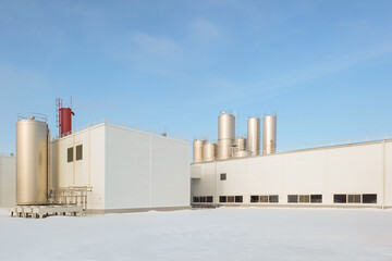 Agro industrial building with outdoor air conditioning units and vertical storage tanks for dairy...