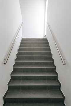Ladder in office building. Steps covered with gray ceramic tiles (porcelain stoneware).