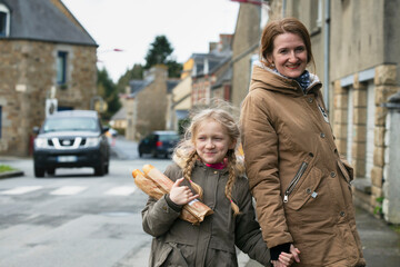 happy mother and daughter with baguettes - 558638392