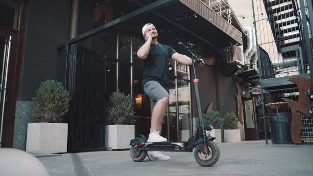 Tourist man on electric scooter with phone in hand. New sharing business project started in city, eco transportation. Slow motion