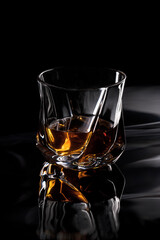 a glass of whiskey on black background