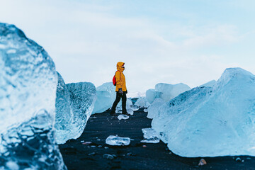 Woman walking along the diamond beach in Iceland. - obrazy, fototapety, plakaty