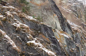 Sheer stone rock with dry grass and snow.