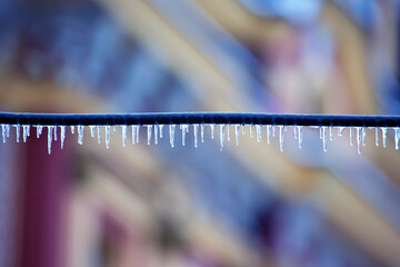 Icicles on wires near street houses. winter season nature