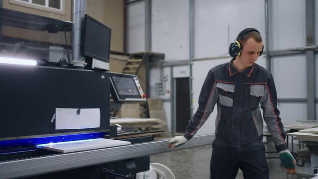 skilled operator of edge banding machine work in industrial workshop of modern furniture factory