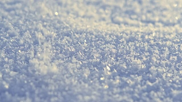 Snow surface. Fresh snow cover. Snowflakes and sparkles on sunny snow texture. Winter background. Small depth of field. Snowy surface with shiny ice crystals. Frozen macro details. Sunny weather day.