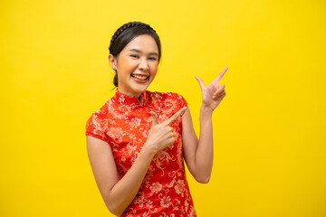 Beautiful Asian woman wearing traditional cheongsam with hand pointing up to copy space isolated on...