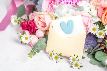 Love letter, envelope with blue heart and card on flower bouquet background