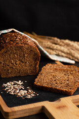 Blurred image of sliced ​​dark bread, healthy seeds on a black background.