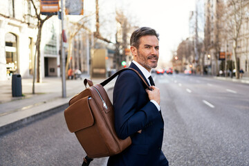 Confident businessman crossing road in city - Powered by Adobe