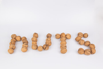 Nuts - an inscription made of walnuts isolated on a white background. Top view, flat lay.