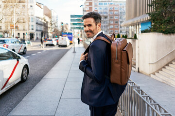 Businessman with backpack walking in city