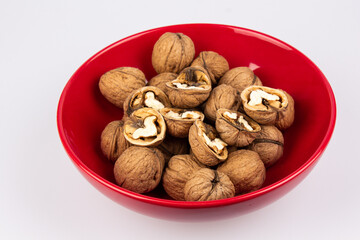 Walnuts in a red bowl isolated on white background. Nuclei in the shape of a heart. Healthy breakfast concept. Valentine's Day.