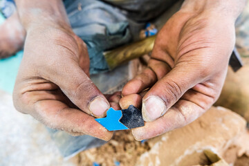Craftsman showing hand made tiny ceramic tiles that perfectly fit each other in pottery factory in Fez, Morocco