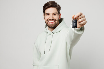 Young smiling cool happy fun caucasian man wears mint hoody look camera hold in hand give car keys...