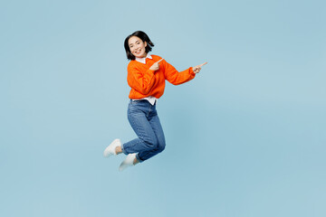 Full body young woman of Asian ethnicity in orange sweater glasses jump high point index finger...