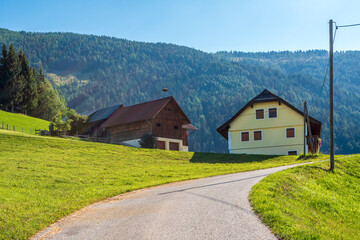 Fototapeta na wymiar Rural houses by country road in Austrian Alps, village of Amberg, Carinthia, Austria.