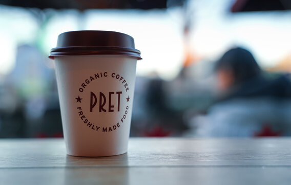 Hand holding a cup of fresh coffee inside a Pret A Manger coffee shop from London, 2023.