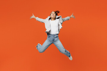 Fototapeta na wymiar Full body young woman of African American ethnicity wears grey shirt headband jump high with outstretched hands legs run to camera isolated on plain orange background studio. People lifestyle concept.