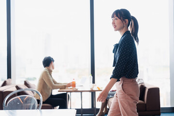 モダンな雰囲気のオフィスのカフェテリアを歩くキャリアウーマン