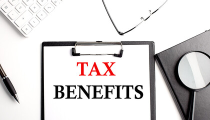 TAX BENEFITS text written on paper clipboard with office tools