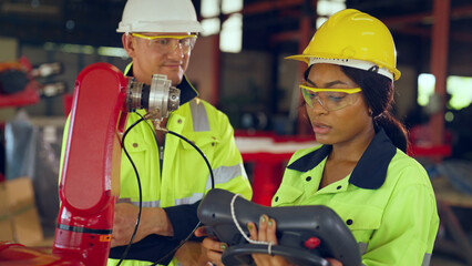 Team engineer examining and develop robot arm together with expertise at lathe factory, worker or...