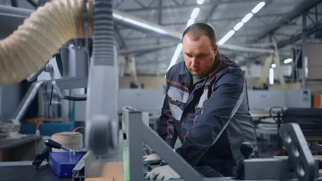 professional operator of CNC machine for sawing wood and chipboard in furniture factory