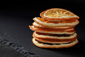 a stack of dried round orange slices on a black background, with a copy of the space