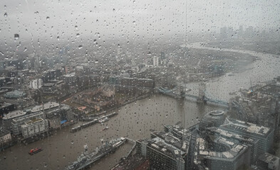 London in cloudy day, drops of rain on the window. Aerial view of London sky scraper buildings and...