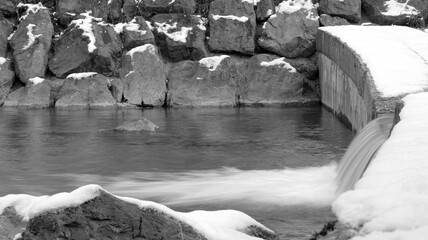 Very small waterfall with foam in winter in black and white