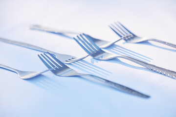 Fork, cutlery and symmetry with eating utensils on a table in an empty studio on a blue background from above. Kitchen, utensil and forks closeup ready for breakfast, lunch or dinner in a restaurant