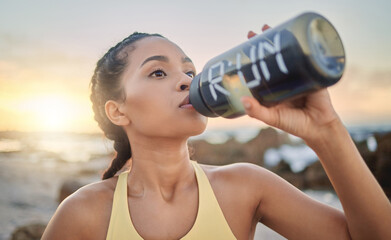 Health, fitness and woman drinking water at beach after running, exercise or workout. Sports,...