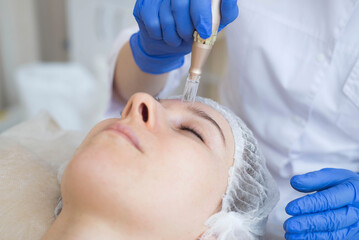 Fototapeta premium Rejuvenating facial treatment. Model is receiving lifting therapy in SPA beauty salon. Exfoliating, stimulating and hydrating.
