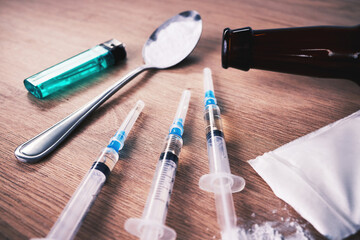 Drugs, syringe and podwer with spoon on table for alcohol addiction, drug rehabilitation and...