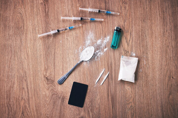 Powder, syringe and drugs with spoon on table for alcohol addiction, drug rehabilitation and narcotics abuse. Medicine problem, crime and illegal drug habit with liquid, cocaine and heroin solution