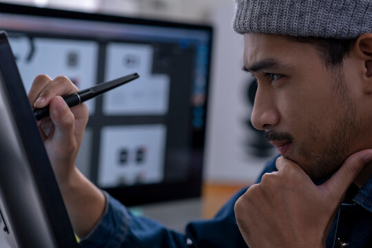 Asian male graphic designer working on computer drawing sketches logo design. The concept of a new brand. Professional creative occupation with idea.
