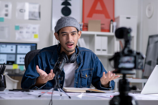 Young Asian male graphic designer blogger influencer talking looking at camera shooting education tutorial vlog training filming video course for social media at studio.