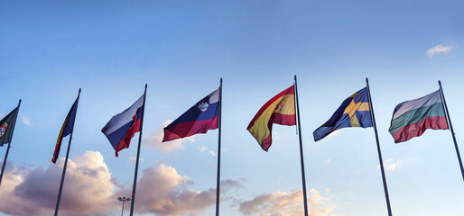 National flags in a row  against sunset blue sky with clouds	