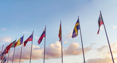 National flags in a row  against sunset blue sky with clouds	