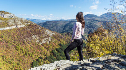 Naklejka premium Traveler Woman standing on a rocks in the autumn mountain . Balkan mountains, ,Bulgaria
