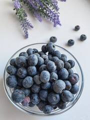 Fresh blueberries in a glass bowl on a white table.