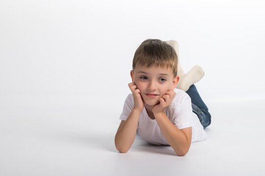 a little boy of European appearance on a white background lies on the floor