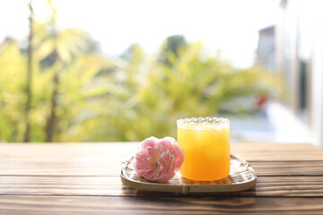 Pineapple juice and pink rose on wooden tray